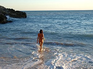 Brunette is ready to do cartwheels while teasing by the water